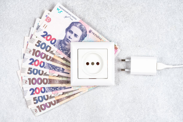 白色插座和插头充电器在UAH货币hryvnyas。乌克兰提高电价的概念。家庭和非家庭消费者用电价格高图片下载