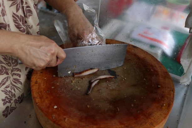 双手正在木条上切烤肉。图片下载