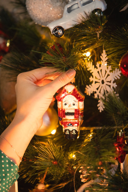 女子手拿胡桃夹子装饰圣诞树玩具图片下载