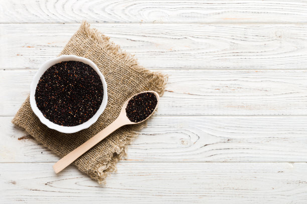 在碗和勺子里的藜麦种子在彩色背景上。健康的kinwa在小碗里。健康的超级食物图片下载