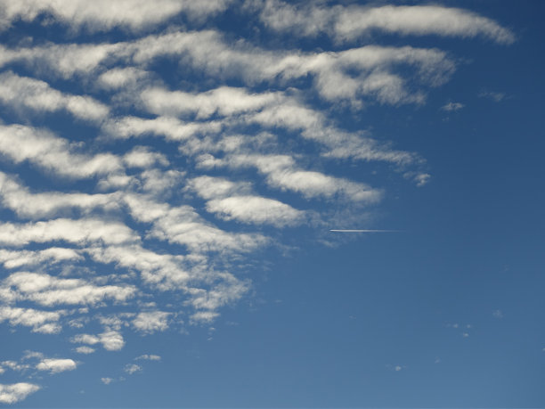 飞机在湛蓝多云的天空上掠过图片下载