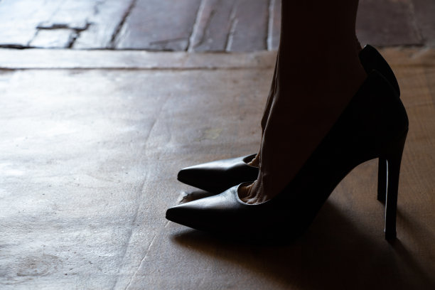 女性脚上穿黑色高跟鞋，在家里的地板上摸黑，女人的鞋子图片下载