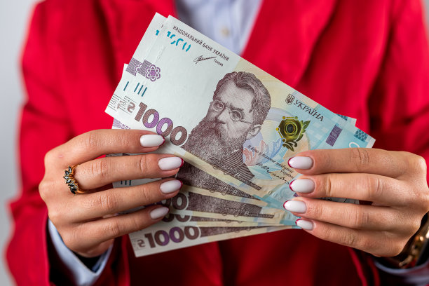 兴奋的快乐的女人站在粉红色的背景穿无肩带连衣裙拿着钱。图片下载