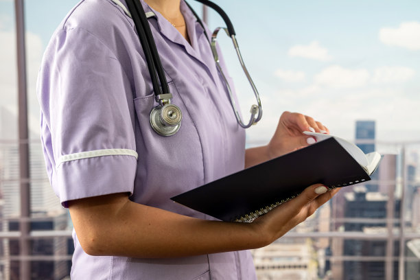 不认识的实习生穿着制服，带着听诊器阅读医学书籍的剪影图片下载