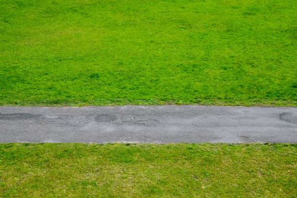 柏油路穿过绿色的草坪，抽象的背景图片下载