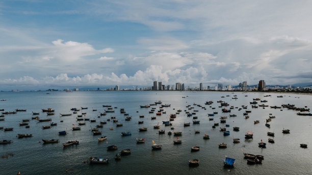 白天越南岘港市的城市景观，摩天大楼和船只在开阔的海上航行图片下载