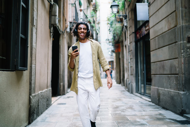 时髦的民族男子戴着耳机走在街上图片下载