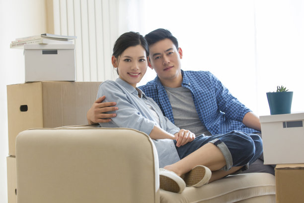 搬进新家后，一对年轻夫妇靠在沙发上，坐在沙发上——照片图片下载