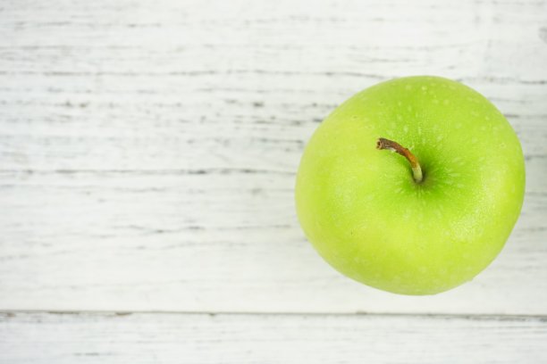 红色和绿色的苹果在木制背景纹理。健康食品的概念图片下载