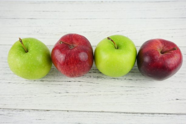 红色和绿色的苹果在木制背景纹理。健康食品的概念图片下载