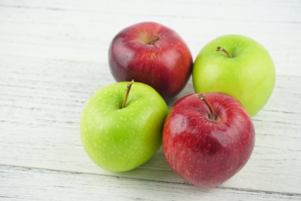 红色和绿色的苹果在木制背景纹理。健康食品的概念图片下载