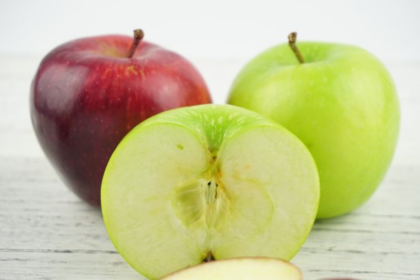 红色和绿色的苹果在木制背景纹理。健康食品的概念图片下载