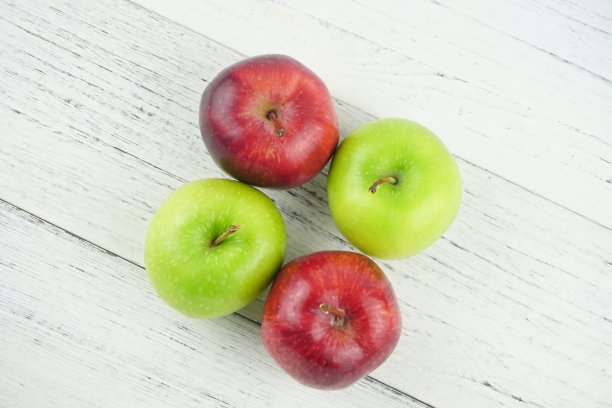 红色和绿色的苹果在木制背景纹理。健康食品的概念图片下载