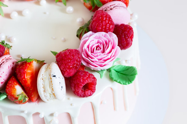 用马卡龙、覆盆子、草莓和糖玫瑰装饰的漂亮的粉色蛋糕。图片下载