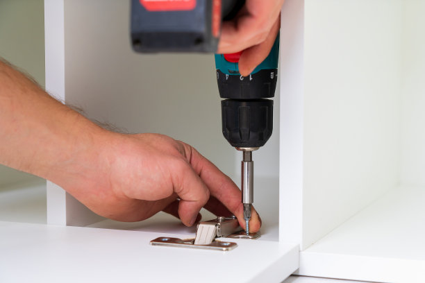 组装家具时，在前门安装铰链。选择聚焦螺丝与模糊的背景图片下载