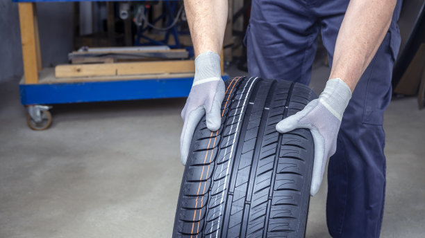 技工的手搬运轮胎在车间进行装配。轮胎穿刺修复。汽车维护安全。图片下载