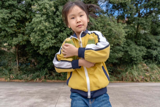 一个亚洲小女孩手里拿着两个木瓜，高兴地跑着图片下载