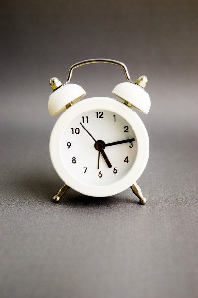 灰色背景上的白色闹钟。文本的空白。图片下载