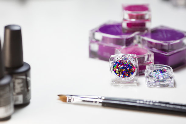 美容工作室。白色背景的修甲材料。刷子，亮片，粉色指甲油。图片下载