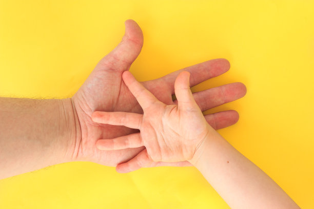 在黄色的背景上，父亲和女儿牵着手。图片下载