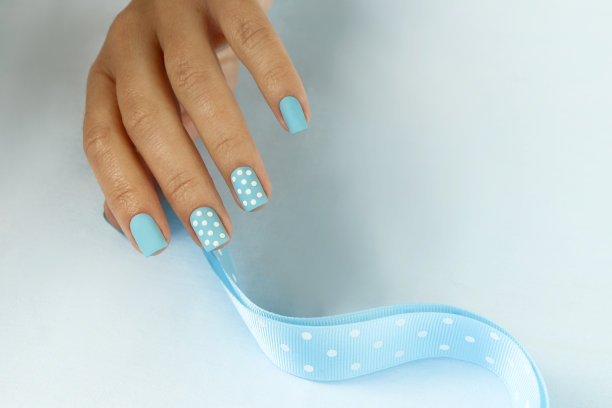 用蓝色指甲油在短指甲上做美甲。图片下载