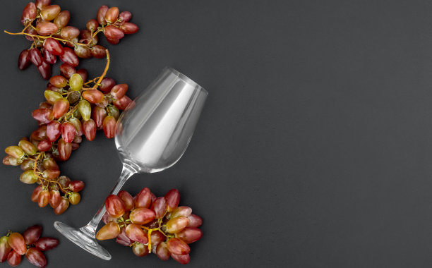 黑色背景上葡萄串的葡萄酒杯。前视图。空间的文本。图片下载