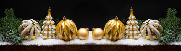 节日的圣诞庆祝节日背景横幅贺卡-金色和黑色的现代圣诞装饰物，圣诞球，圣诞树和松树枝在雪木桌图片下载