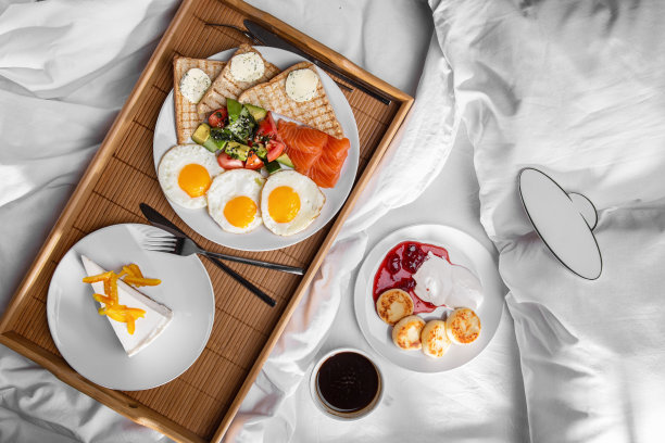 烤面包配三文鱼片、牛油果、黄瓜、芝麻、西红柿、煎蛋和黄油配欧芹、奶酪蛋糕配杏片放在木板上、奶酪馅饼装在盘子里、酸奶油和果酱放在白桌子上图片下载