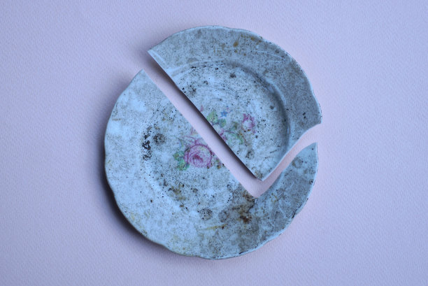 一块破的、脏的、带图案的圆形陶瓷板图片下载