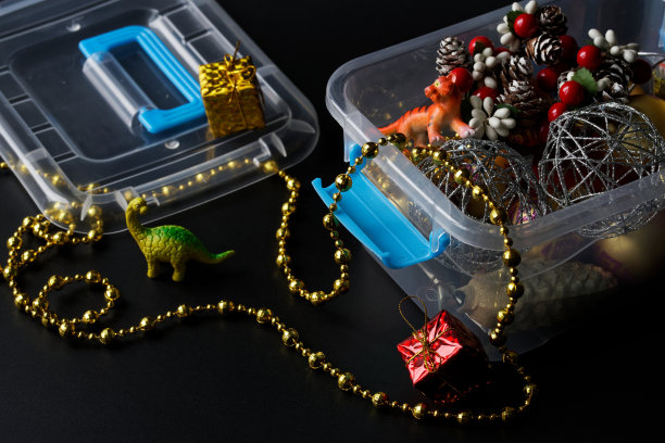 装有圣诞和新年玩具和装饰品的塑料容器。寒假的概念和装饰房子和圣诞树。可爱的家庭装饰。黑暗的背景。图片下载