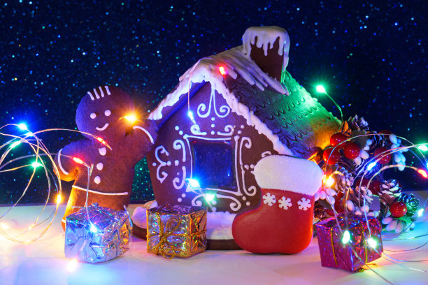 姜饼冬天的房子，彩色盒子里的礼物，姜饼人和白色和闪闪发光的蓝色背景上的灯。设计圣诞快乐和新年快乐的贺卡。图片下载