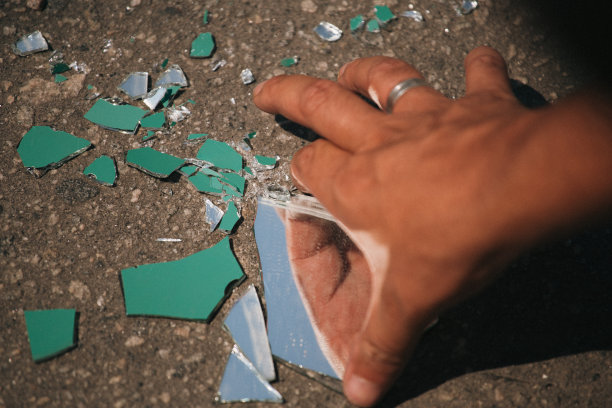 一只手捡起镜子碎片的特写镜头图片下载