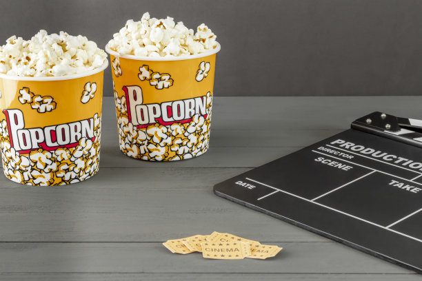 爆米花桶旁边的隔板和灰色背景的电影票的特写镜头图片下载
