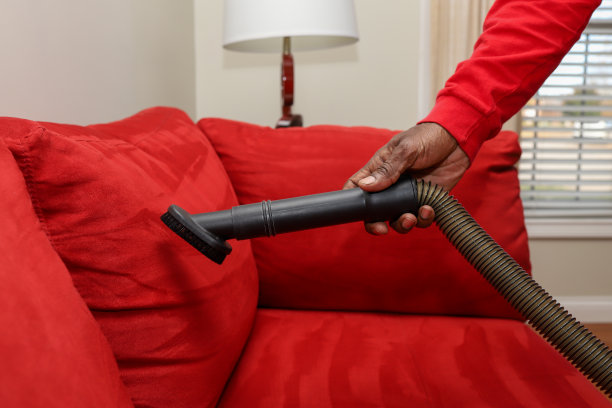 一个黑人在用吸尘器清扫沙发图片下载