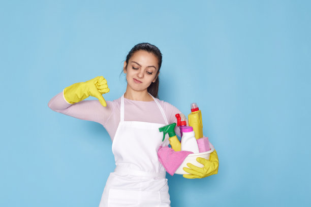 戴着黄色手套和清洁围裙的女人用海绵表示拒绝和否定，拇指朝下图片下载