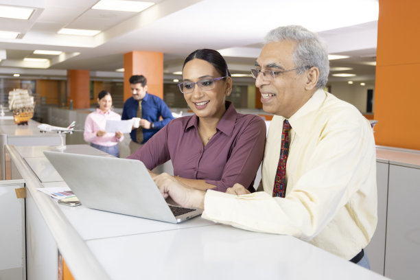 高级商人和妇女在办公室使用笔记本电脑。图片下载