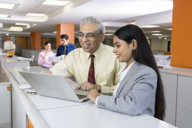 高级商人和妇女在办公室使用笔记本电脑。图片下载