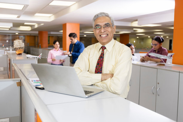 高级商人的肖像与笔记本电脑在办公室。图片下载