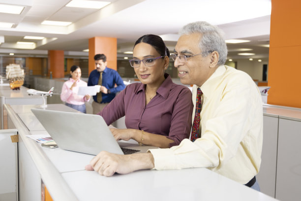 高级商人和妇女在办公室使用笔记本电脑。图片下载