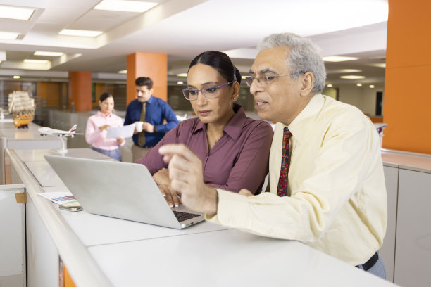 高级商人和妇女在办公室使用笔记本电脑。图片下载