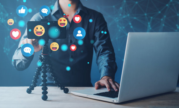 一名男子正在用智能手机和虚拟表情符号社交媒体图标在线直播内容。带耳机的Streamer与听众交谈。新概念视频博客。图片下载