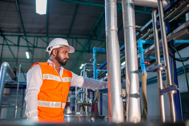 亚洲工程师工人穿着安全制服在工业工厂控制操作机器和打开开关。图片下载