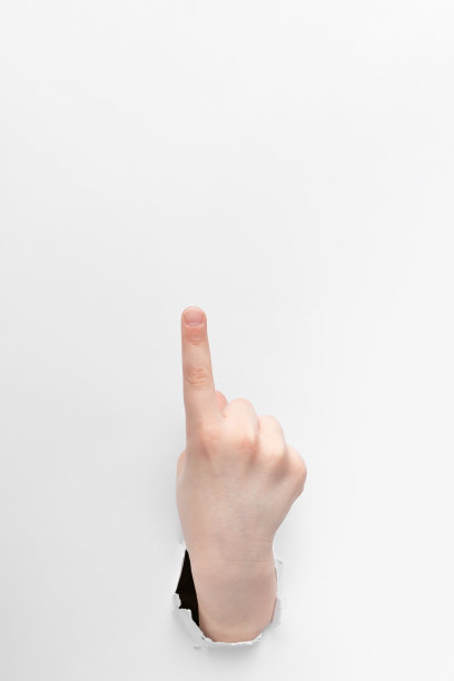 孩子的手在白纸上用撕破的边缘露出食指向上穿过的小孔，注意的概念与复制的空间图片下载