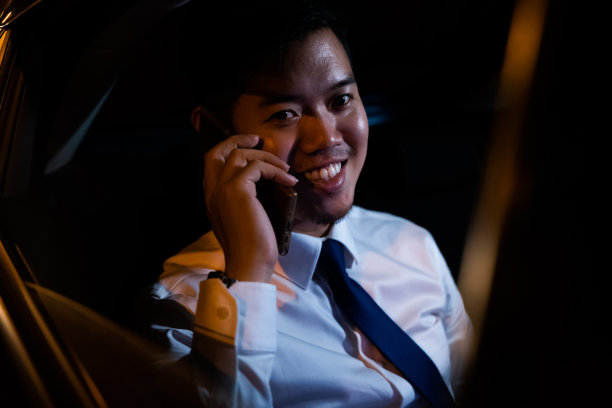 商人晚上在靠窗的汽车后座上使用智能手机图片下载