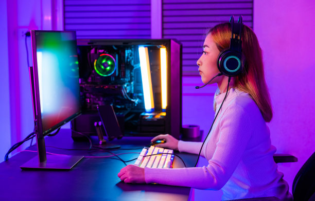 亚洲职业玩家在台式电脑上玩在线视频游戏，电脑上有五颜六色的霓虹LED灯图片下载