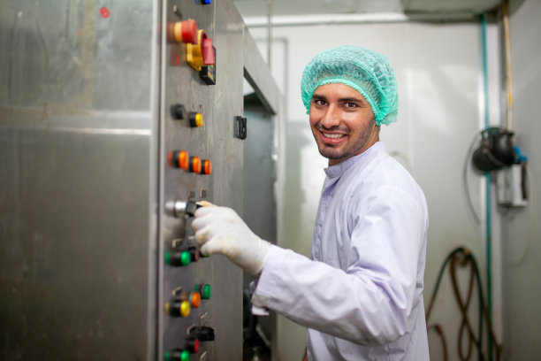 在饮料厂的生产线上，工人正在控制操作机器和打开开关。图片下载