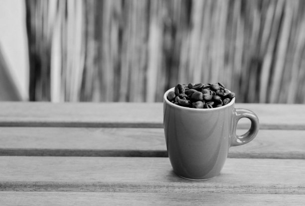 在木桌上，用灰度特写拍摄了两个装满烘焙咖啡豆的杯子图片下载