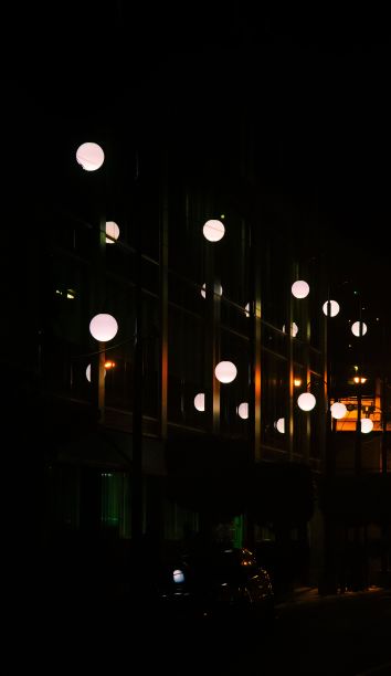 夜晚，街灯在建筑物窗户上反射的垂直照片图片下载