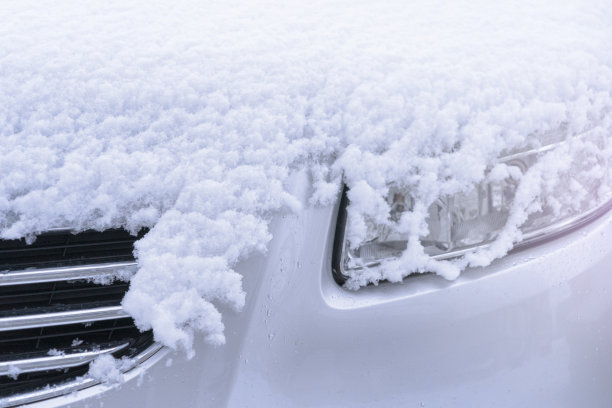雪地里的汽车前灯。雪天结冰的汽车图片下载
