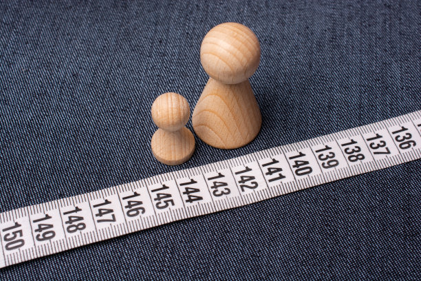 顶视图的软裁缝卷尺上的牛仔裤材料与小木制雕像图片下载